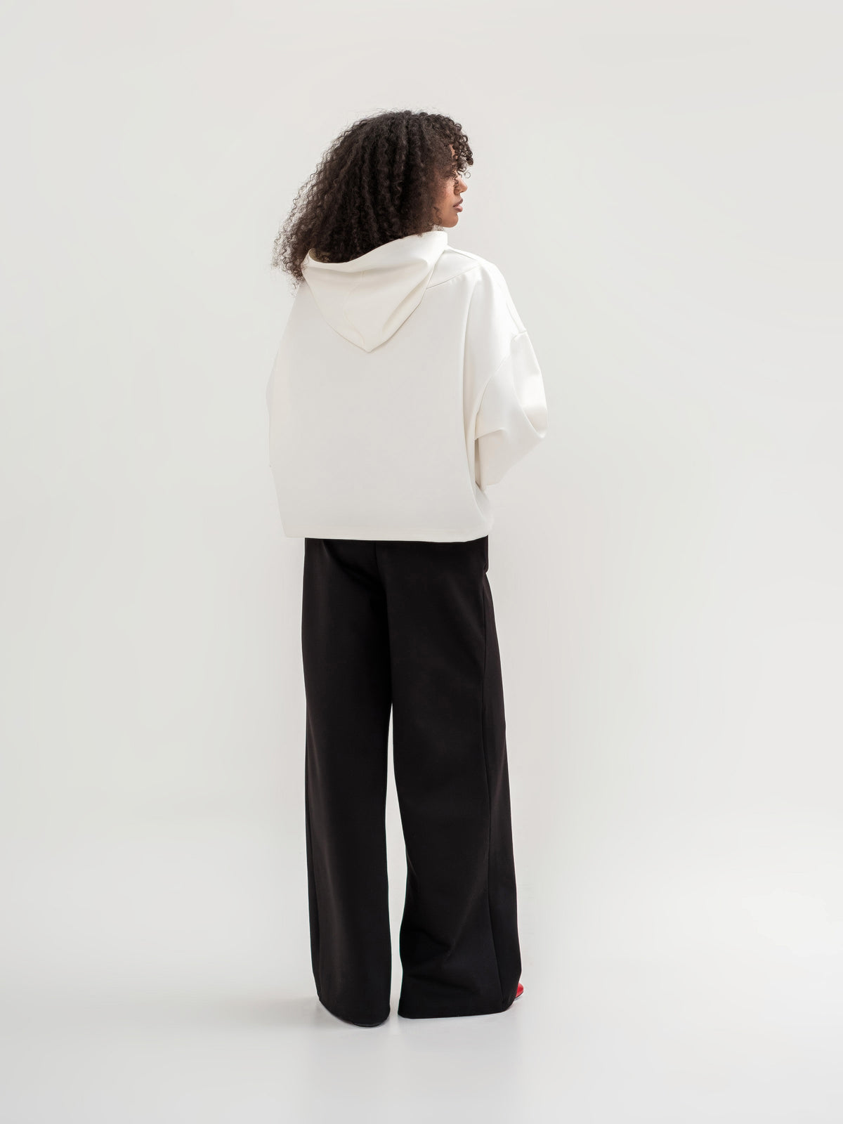 White hoodie with zip shoulder area on the back and black wide leg trousers