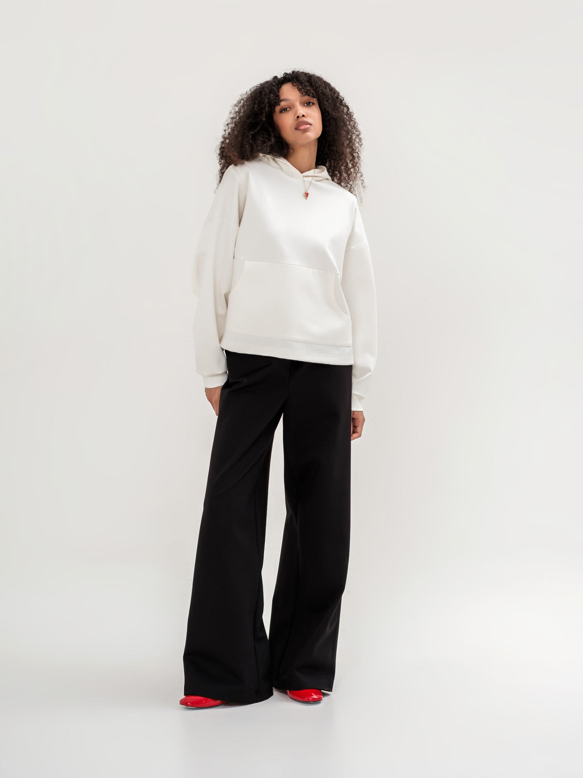 White hoodie with a zipper in the shoulder area on the back and  black wide leg trousers 