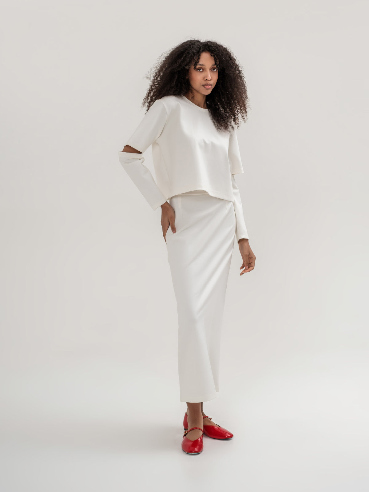 White top with slits in the elbow area and white straight long skirt with slit on the back