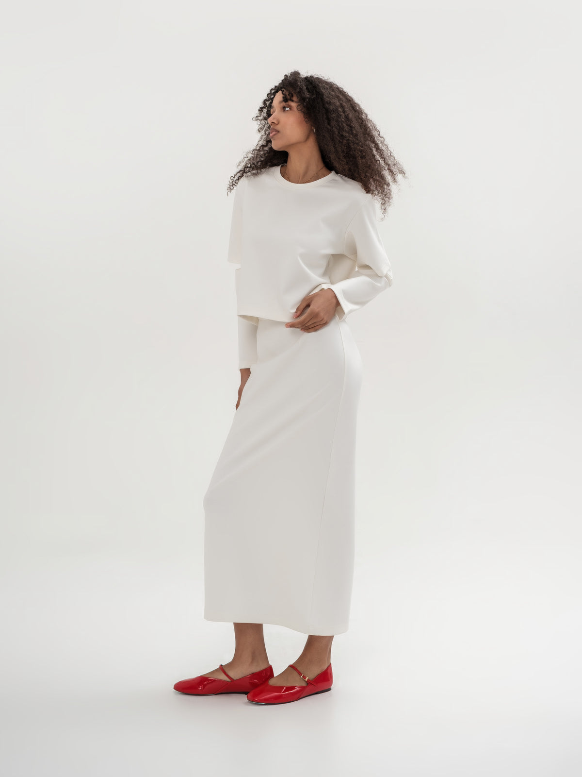 White top with slits in the elbow area and white straight long skirt with slit on the back